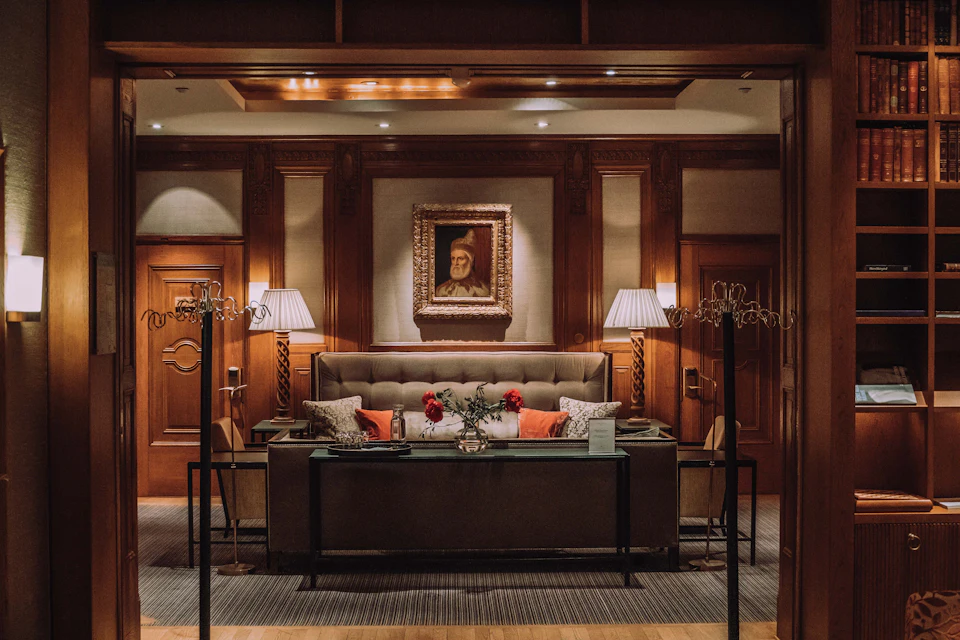A wood-panelled hotel lounge with a sofa and lamps