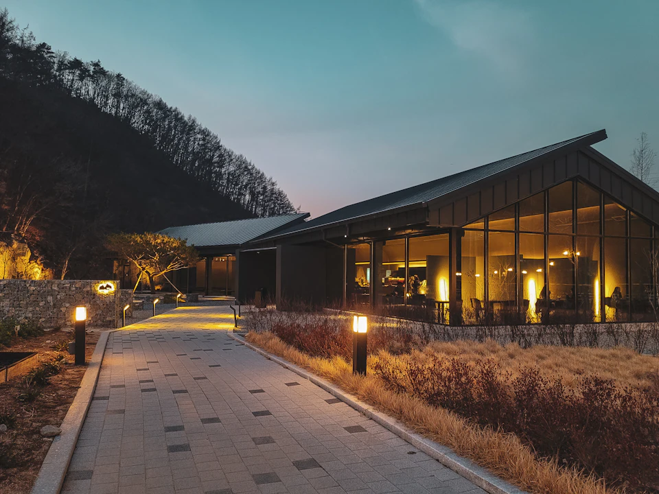 A resort lodge lit at dusk at the end of a garden path