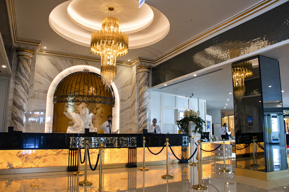 Hotel reception staff at a marble front desk beneath a chandelier